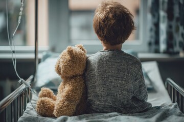 A frightened young boy with an IV and a teddy bear sits on a hospital bed gazing out the window of a pediatric ward before surgery
