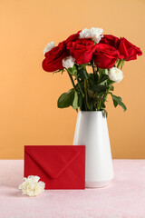 Vase with beautiful flowers and envelope on pink table against color wall