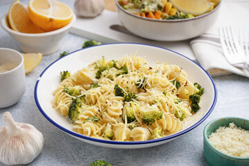 Delicious fusilli pasta with broccoli and cheese in bowl on light background, closeup