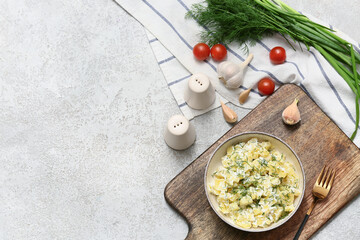 Bowl of tasty potato salad with dill, green onion, tomatoes and garlic on grey grunge background