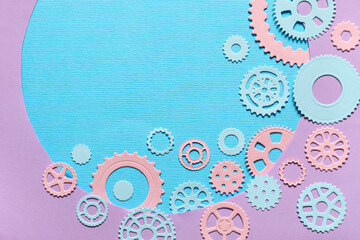 Different figures of gears on blue background visible through cut lilac paper