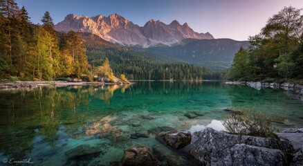 Fototapeta premium Serene mountain lake at sunrise reflecting peaks and lush trees, ideal for nature enthusiasts