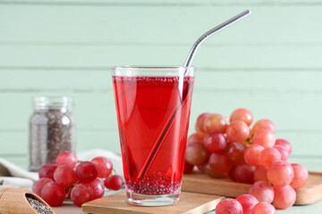 Glass of lemonade with chia seeds and grape on green wooden table, closeup