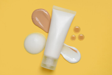 Tube of cosmetic product and different samples on yellow background
