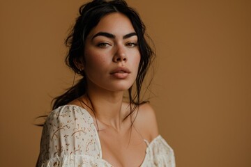 Portrait of a beautiful young woman in a white dress on a brown background