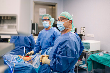 Surgeons observing and coordinating surgical actions while performing laparoscopic knee procedure...