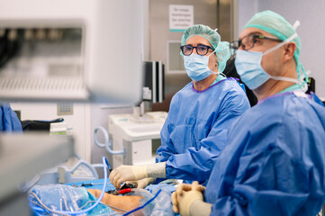 Medical team in surgical room concentrating on monitor during orthopedic knee operation procedure