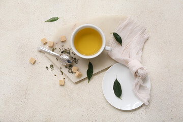 Cup of hot green tea with sugar cubes, strainer and dried leaves on white background