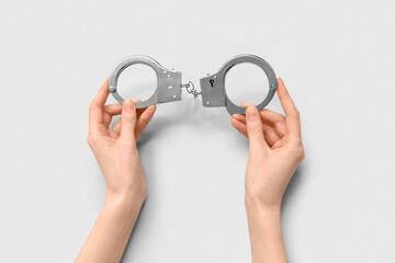 Female hands with handcuffs on white background