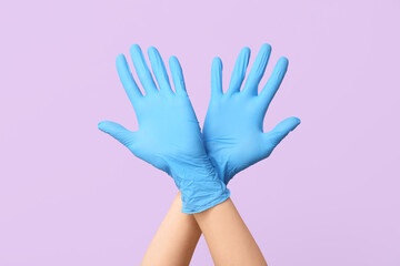 Female hands in medical gloves on lilac background