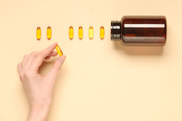 Female hand with bottle of fish oil capsules on color background, closeup