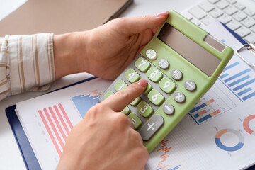 Female accountant with calculator and financial graphics at table in office