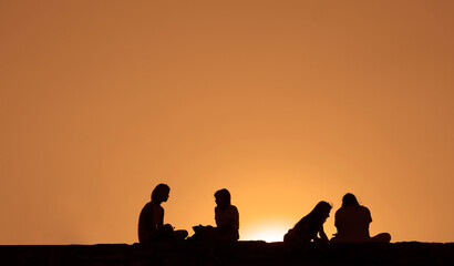 Silhouette back rear view of couple group people friends team sitting together on sunset sky evening time for business success and teamwork concept in company. Kalemegdan fortress. sunrays bokeh