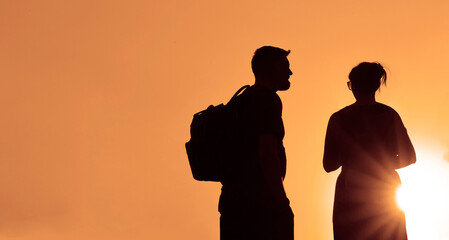 black silhouette of couple in the park. happy family walking silhouette at sunset. man woman walking. happy pair.  sun go back on sunset sky background