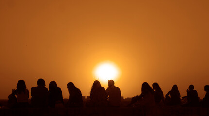 Silhouette back rear view of group happy people friends team sitting together on sunset sky evening time for business success and teamwork concept in company. Kalemegdan fortress. sunrays bokeh