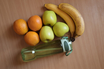 pile of green apples,  orange and bunch of bananas on the wooden background, closeup. empty copy...