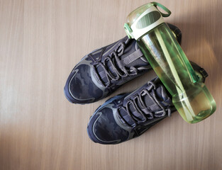 Running tourism sporty brandless shoes, green plastic bottle of aqua water on wooden floor...