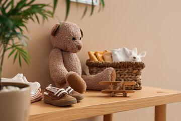 Toys with baby clothes on bench near beige wall, closeup