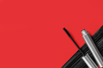 Black mascara in silver tube with sample on red background