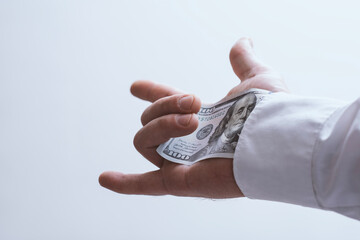 Close-up of a male hand pulling a dollar bill from the sleeve of a white shirt. Symbol of corruption, bribery, hidden transactions and secret payment.