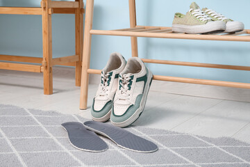 Sneakers with orthopedic insoles on rug in hallway, closeup