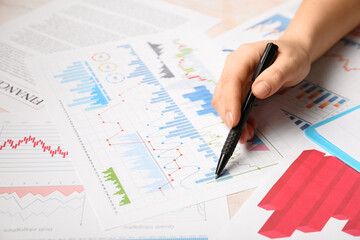 Female hand with pen and business charts on white background