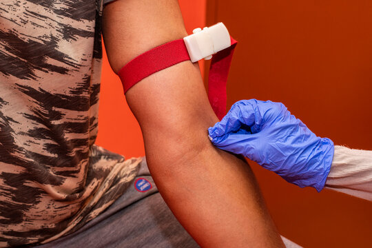 Professional phlebotomist drawing blood sample from adult male patient in clinical setting - Powered by Adobe