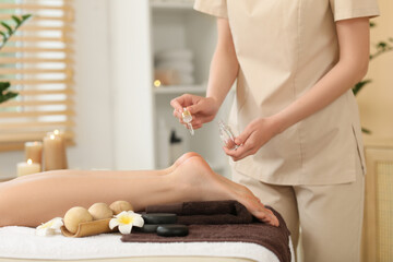 Female therapist applying massage oil on woman's feet in spa salon