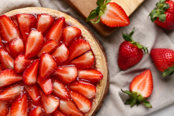 Wooden board with sweet strawberry tart on napkin, closeup