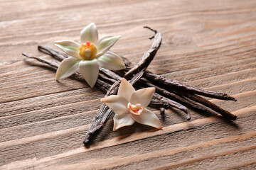Vanilla sticks and flowers on wooden background