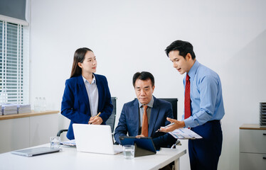 Asian executives discussing financial data and charts in a modern office setting. Teamwork,...