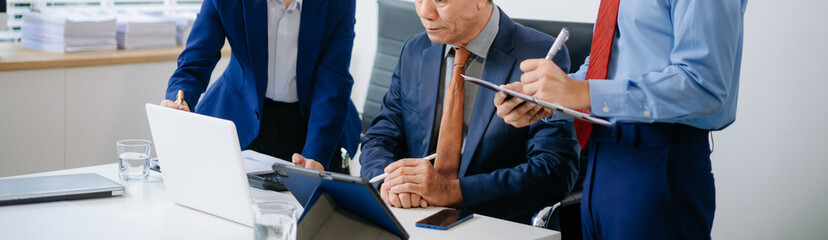 Asian executives discussing financial data and charts in a modern office setting. Teamwork, decision making, leadership