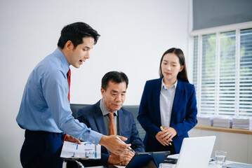 Asian executives discussing financial data and charts in a modern office setting. Teamwork, decision making, leadership