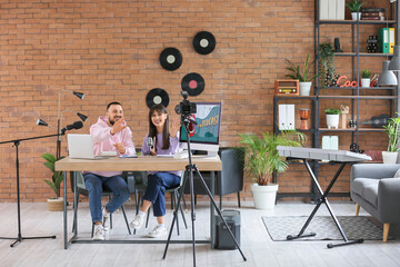 Young couple recording podcast at table in studio