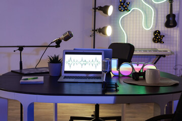 Podcaster's workplace with laptops and microphones in dark studio