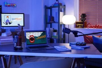 Podcaster's workplace with laptop and microphones in dark studio