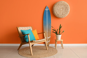 Armchair, houseplant and surfboard near orange wall in interior of living room