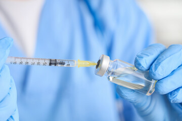 Female doctor with vaccine and syringe in clinic, closeup