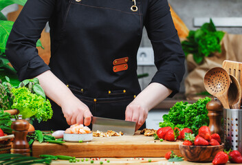 Chef expertly chops walnuts s while preparing a vegan meal, surrounded by fresh ingredients in a warm kitchen setting.