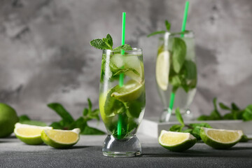 Glass of tasty mojito and ingredients on grey grunge background, closeup
