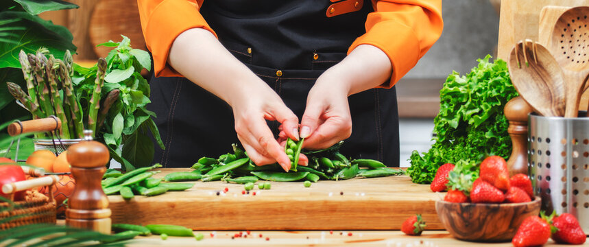 Woman preparing green peas and fresh vegetables in a modern kitchen while promoting healthy vegan cooking for her lifestyle blog