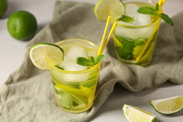 Composition with glasses of tasty mojito, napkin and limes on white background, closeup