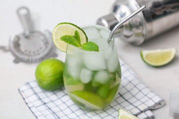 Glass of tasty mojito, napkin and ingredients on white background, closeup