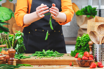 Chef prepares fresh green peas and vegetables and strawberries in a vibrant kitchen setting focused on healthy vegan cooking