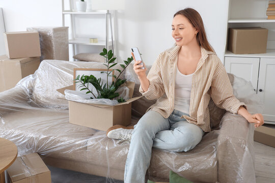 Young woman using mobile phone in room on moving day - Powered by Adobe