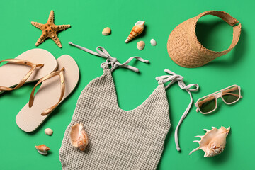 Summer composition with swimsuit, seashells and beach accessories on green background, closeup