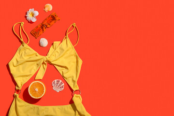 Summer composition with swimsuit, sunglasses and orange on color background
