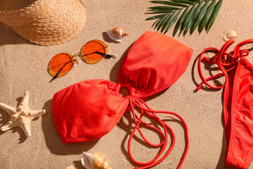 Summer composition with swimsuit, sunglasses and seashells on sand as background, closeup