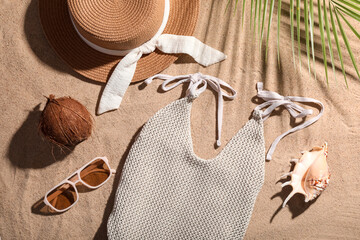Composition with swimsuit, coconut and beach accessories on sand as background, closeup
