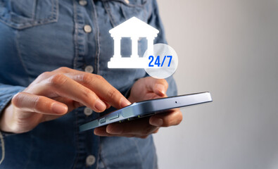 Close-up of a woman's hands holding a smartphone with bank icons and numbers 24/7. The concept of...